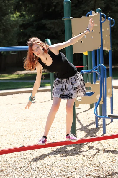 Young teen girl balancing on red bar — Stock Photo, Image