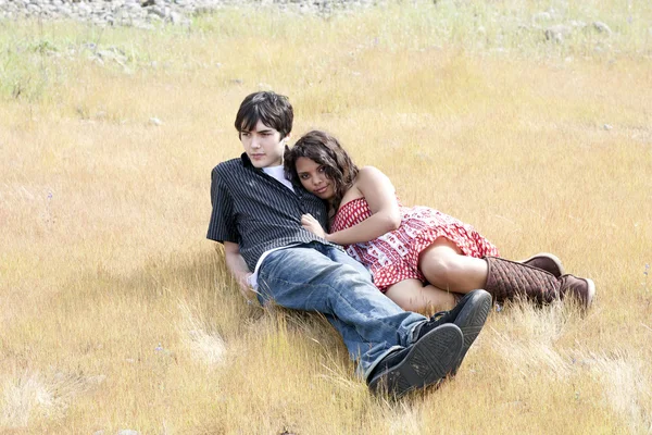 Młoda para nastolatków, leżącej na zewnątrz w żółty trawa — Zdjęcie stockowe