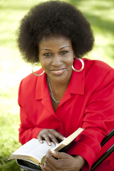 Чорна жінка середнього віку на відкритому повітрі читає Біблійну посмішку — стокове фото