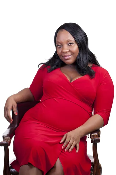 若い黒椅子赤いドレスに座って妊娠中の女性 — ストック写真