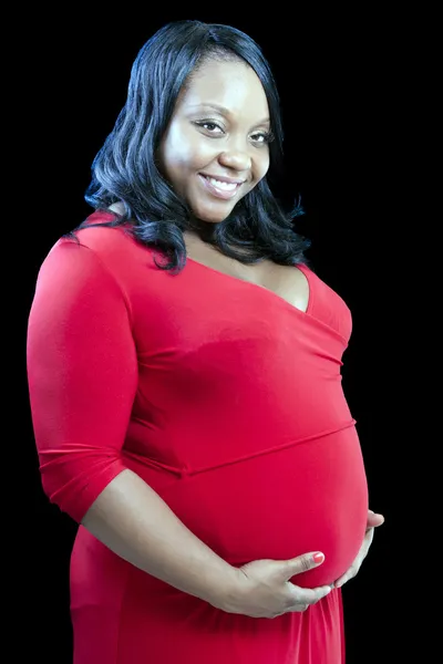 Joven mujer embarazada negro sosteniendo el vientre vestido rojo — Foto de Stock