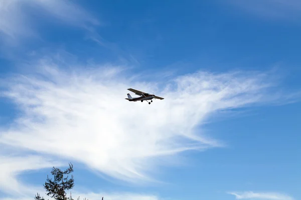 Horizontal shot of small plane in blue sky and white cirrus clouds