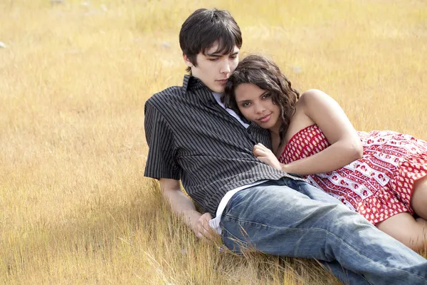 Jovem casal adolescente reclinado na grama amarela — Fotografia de Stock