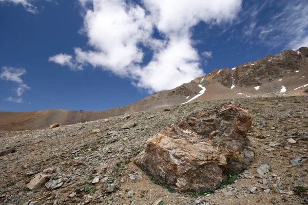 Kamienny blok w górskiej dolinie przeciw błękitne niebo i chmury. — Zdjęcie stockowe