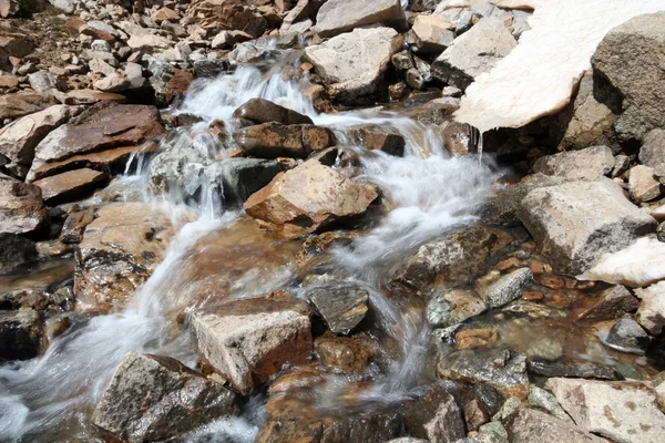 Flowing glacier stream among stones. Caucasus mountains. — Stock Photo, Image