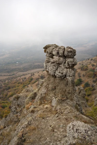 Rock column against valley in fog.Crimea mountains. — Stock Photo, Image