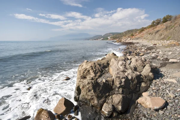 Mořské pobřeží s pěnou, kameny, oblázky a kameny — Stock fotografie