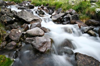 Stream of mountain river among stones and boulders clipart