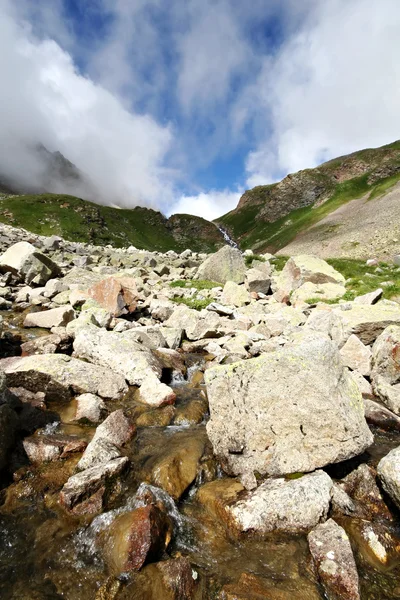 Fließender Gletscherbach zwischen Steinen. Kaukasusgebirge. — Stockfoto