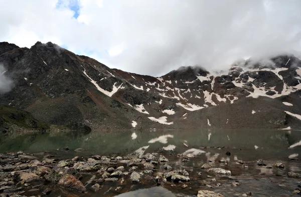 Lago di montagna con riflesso. Pietre, foschia, rocce. Caucaso . — Foto Stock