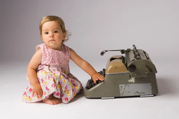 Κορίτσι μωρό ποζάρει με γραφομηχανή — Φωτογραφία Αρχείου