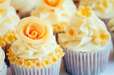 Cupcakes decorated with yellow sugar roses clipart