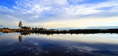 A dramatic sky reflecting in a calm northern lake clipart