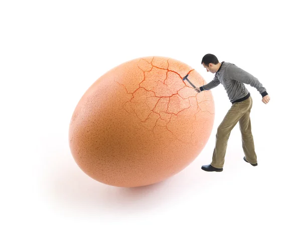 Jeune homme craquant un œuf à l'aide d'un marteau Image En Vente