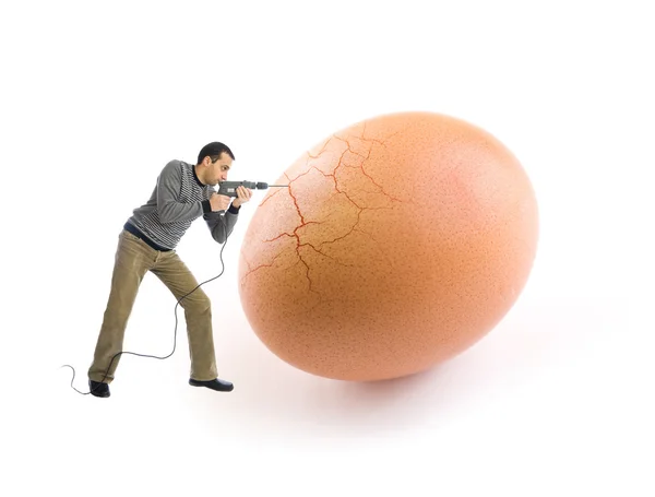 Jeune homme craquant un œuf à l'aide d'un outil de forage Images De Stock Libres De Droits