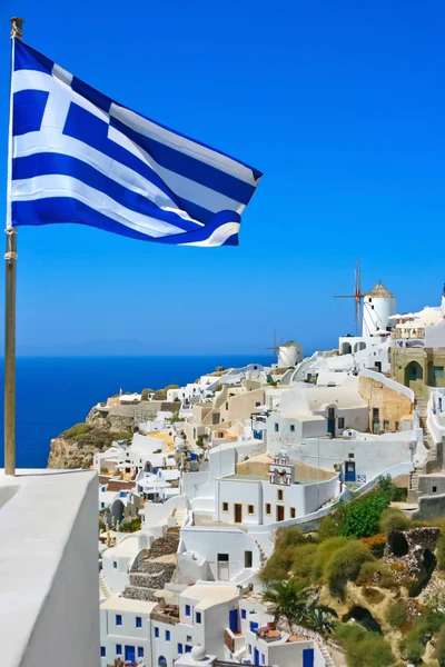 Hermoso molino de viento de Oia con bandera nacional de Grecia Imagen de stock