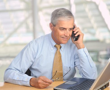 Businessman with laptop and phone clipart