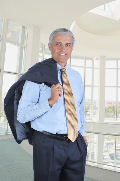 ロビー 近代的なオフィスビルで彼のジャケットの肩の上の中間の高齢者ビジネスマン 垂直方向の形式 — ストック写真