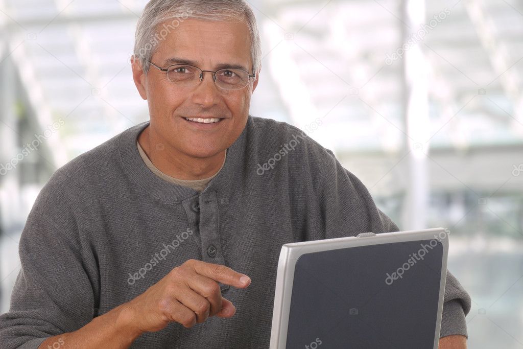 Middle aged man in lobby of modern office building laptop comput