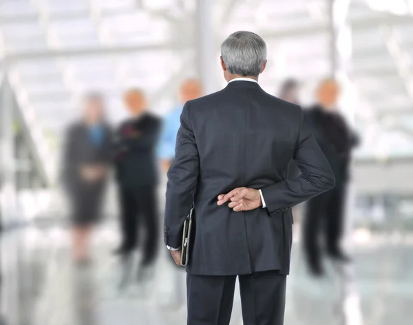 Empresário de pé com os dedos cruzados atrás das costas — Fotografia de Stock
