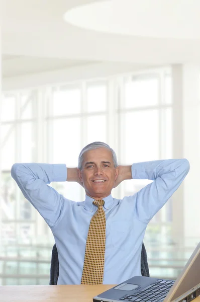 Mann am Schreibtisch mit den Händen hinter dem Kopf — Stockfoto
