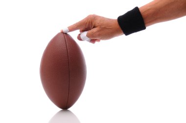 Hand holding a football ready for kicking clipart