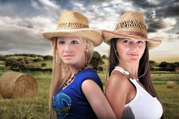 Dwie dziewczyny w kowbojskich kapeluszach i uśmiechając się — Zdjęcie stockowe