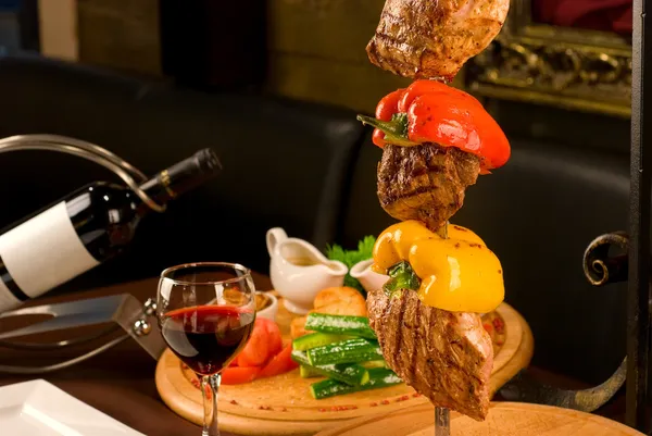 大きなおいしいロースト肉を串飾られたテーブルの上にカットします — ストック写真