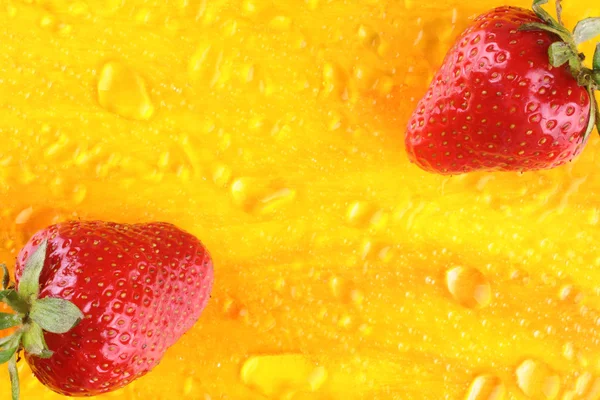 Two strawberries and water drops on yellow background — ストック写真
