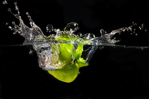 stock image A falling star fruit plunges into the water creating a large splash