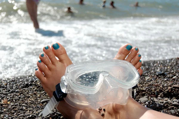 De benen van de vrouw op het strand van de zee met een duikbril. — Stok fotoğraf