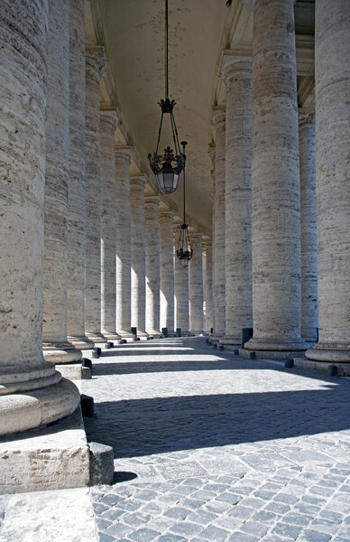 The geometric architecture of the columns and curved hallway towards the saint peter basilica