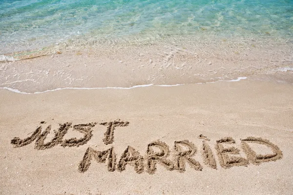 結婚したばかりな砂の上に書かれました。 ストックフォト