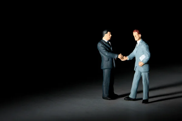 Figuras em miniatura de empresários que apertam a mão — Fotografia de Stock