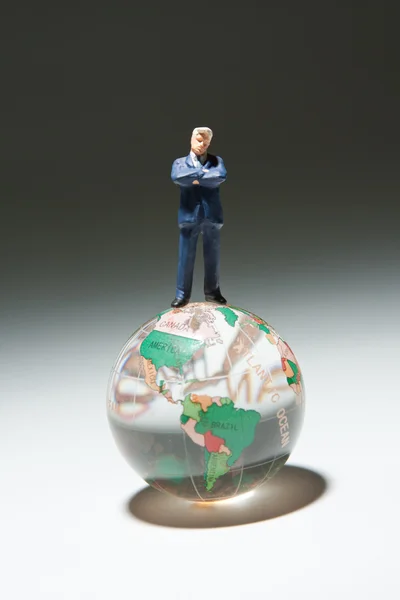 ガラス グローブ上に立っているビジネスマンの置物 — ストック写真