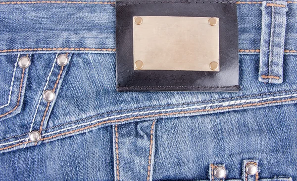 Blue jeans with bronze label — Stock Photo, Image