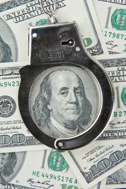 Close-up of handcuffs on one hundred banknotes clipart