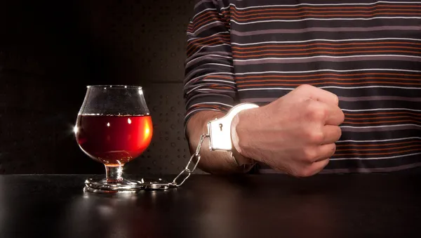 Mão trancada no copo de álcool — Fotografia de Stock