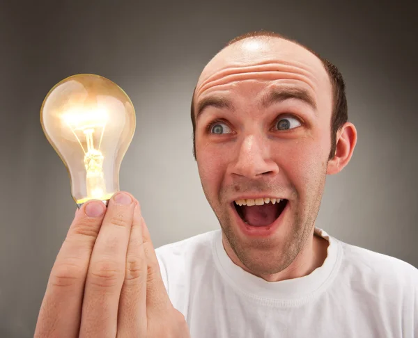 Hombre sorprendido sosteniendo bombilla de iluminación — Foto de Stock