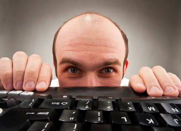 Timid nerd escondido sob o teclado do computador — Fotografia de Stock