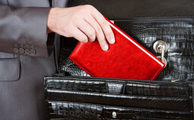 Hand taking red organizer from briefcase clipart