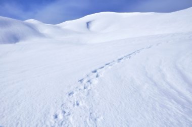Footprint of hikers in the snow round a mountain clipart