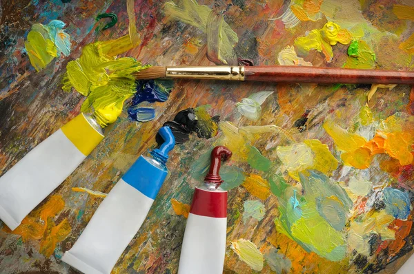 Paleta con pincel y tubos de pintura al óleo — Foto de Stock