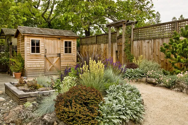 小さな木製の小屋 フェンスと経路の美しく手入れされた裏庭 ロイヤリティフリーのストック画像