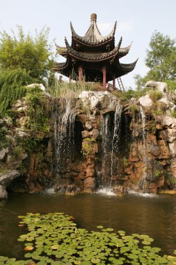 China. Waterfall, the ancient Chinese temple and a pond clipart