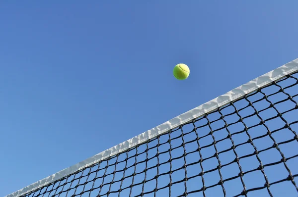 Жовтий тенісний м'яч літає мережею — стокове фото