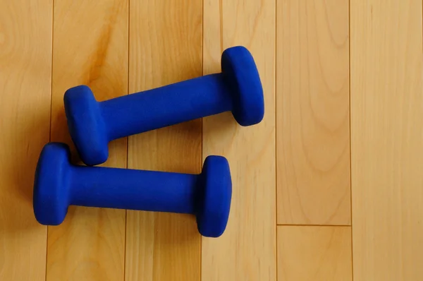 Pesos azuis no piso de madeira do Fitness Center — Fotografia de Stock