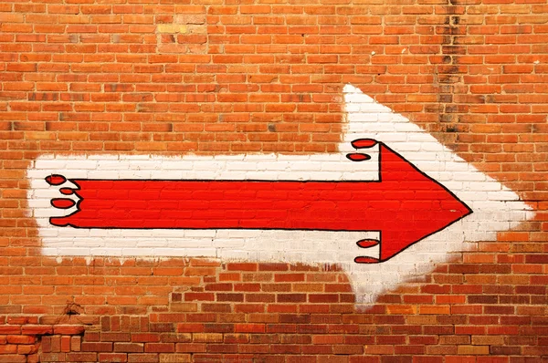 Kırmızı ok bir tuğla duvara boyalı — Stok fotoğraf