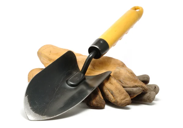 Старые грязные кожаные рабочие перчатки и лопатки — стоковое фото
