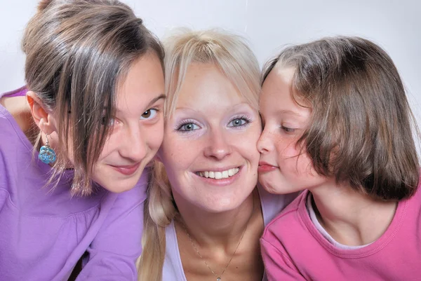 Una madre sonríe mientras recibe un beso en la mejilla de su —  Fotos de Stock